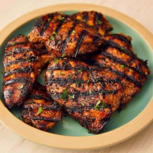 frango grelhado dentrod e um prato, o frango é levemente avermelhado com marcas de queimado da grelha