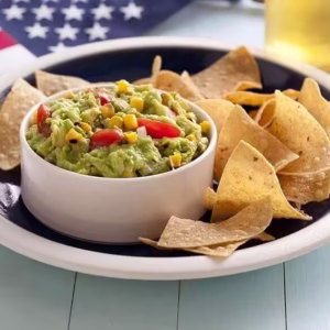 Guacamole com chips de tortilla em um prato com bandeira americana ao fundo