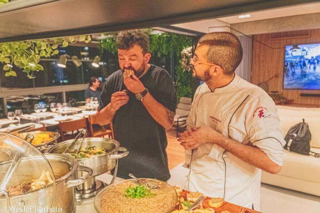 Chef Dom Barbato conversando com um convidado enquanto prova a comida