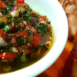 Tigela branca com vinagrete colorido de tomate, cebola roxa, pimentão e cheiro-verde em óleo, ao lado de prato com feijoada