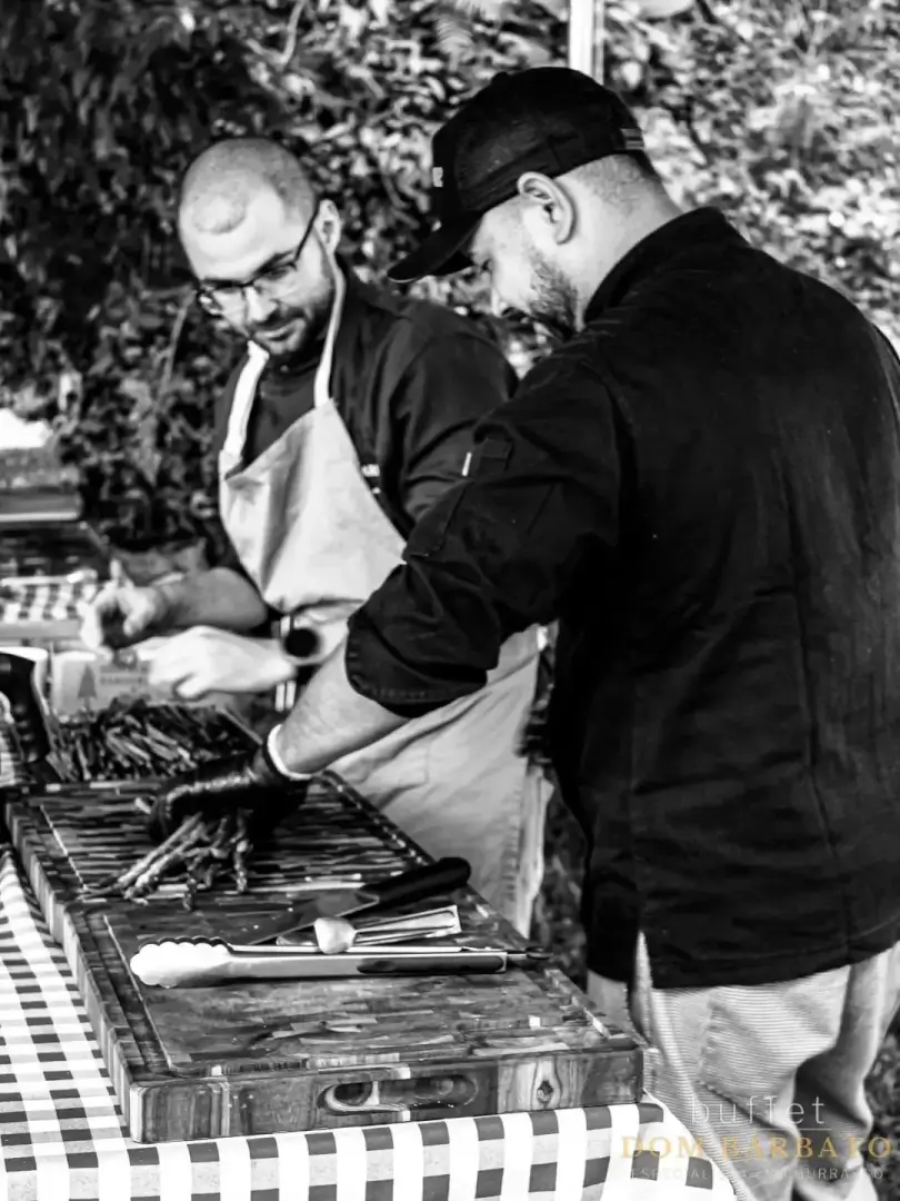 Chef Dom e churrasqueiro preparam carnes na estação de corte em evento do Dom Barbato Buffet
