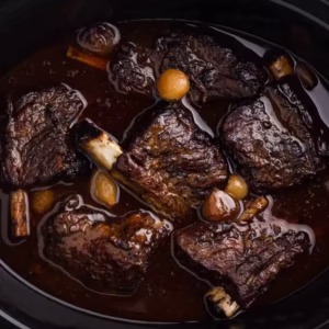 Costelas bovinas short ribs cozidas lentamente em molho escuro com cebolas pérola em panela slow cooker