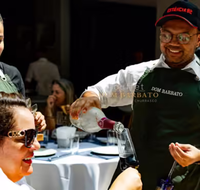 Chef Dom servindo bebida para convidada em evento de churrasco premium ao ar livre