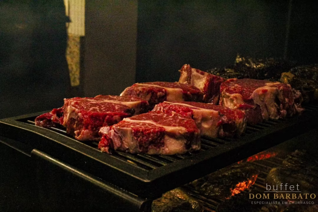 Cortes de carne bovina crua sobre grelha com brasas ao fundo, buffet Dom Barbato