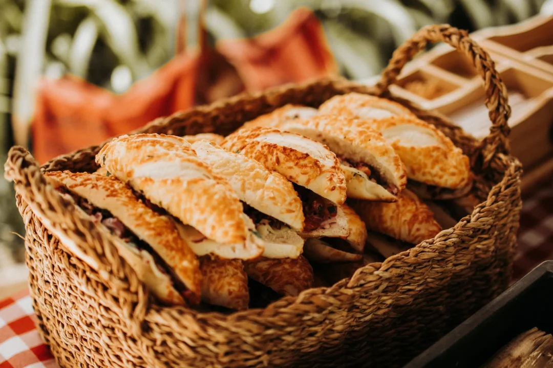 Wicker basket filled with toasted baguette sandwiches with melted cheese and various fillings