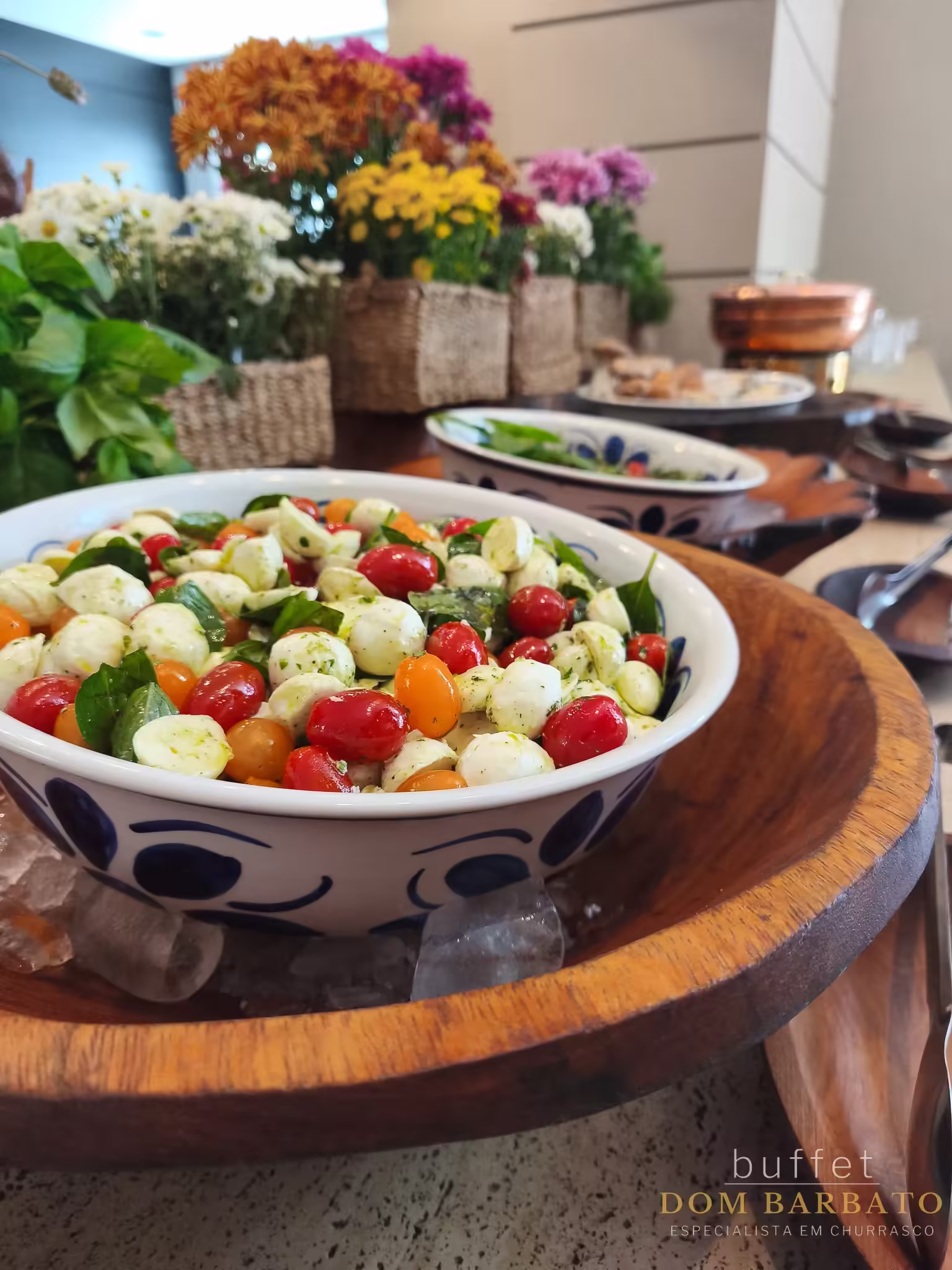 Tigela branca com bolinhas azuis contendo salada caprese com tomates cereja coloridos, mozzarella e manjericão