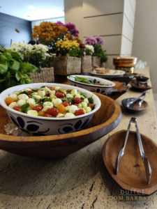 Bowl de cerâmica com salada caprese de tomates coloridos, mussarela e manjericão dentro de bowl de madeira