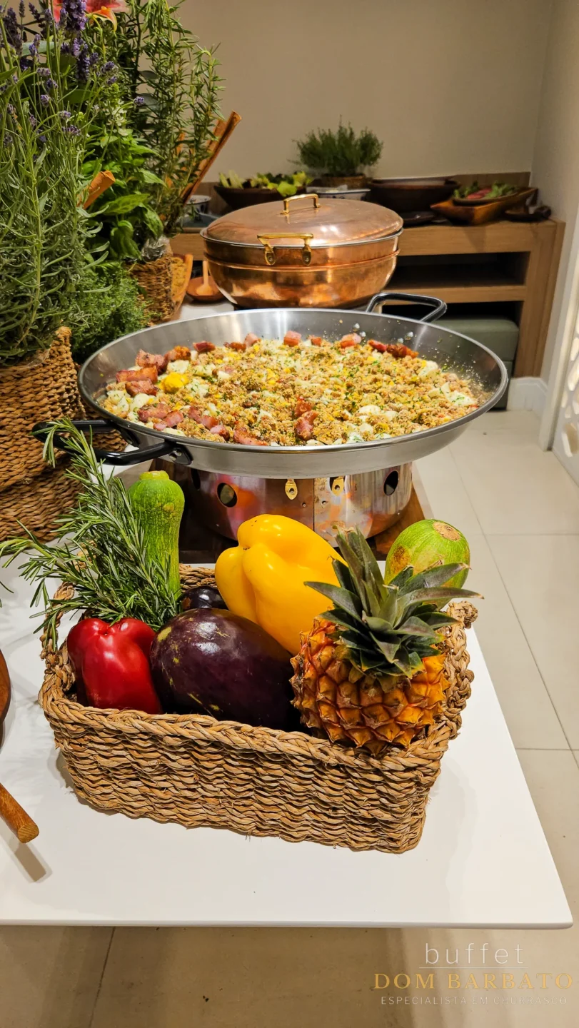 Large paella pan with rice and vegetables, fresh produce basket with pineapple red pepper eggplant, potted herbs, copper cookware, kitchen counter