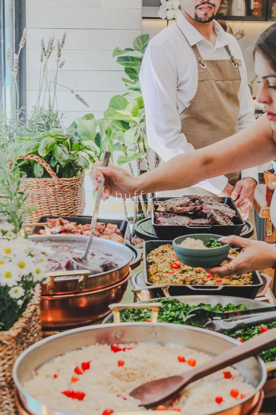 Buffet com panelas de cobre contendo feijoada, arroz branco, farofa e carnes, atendente servindo comida em tigela
