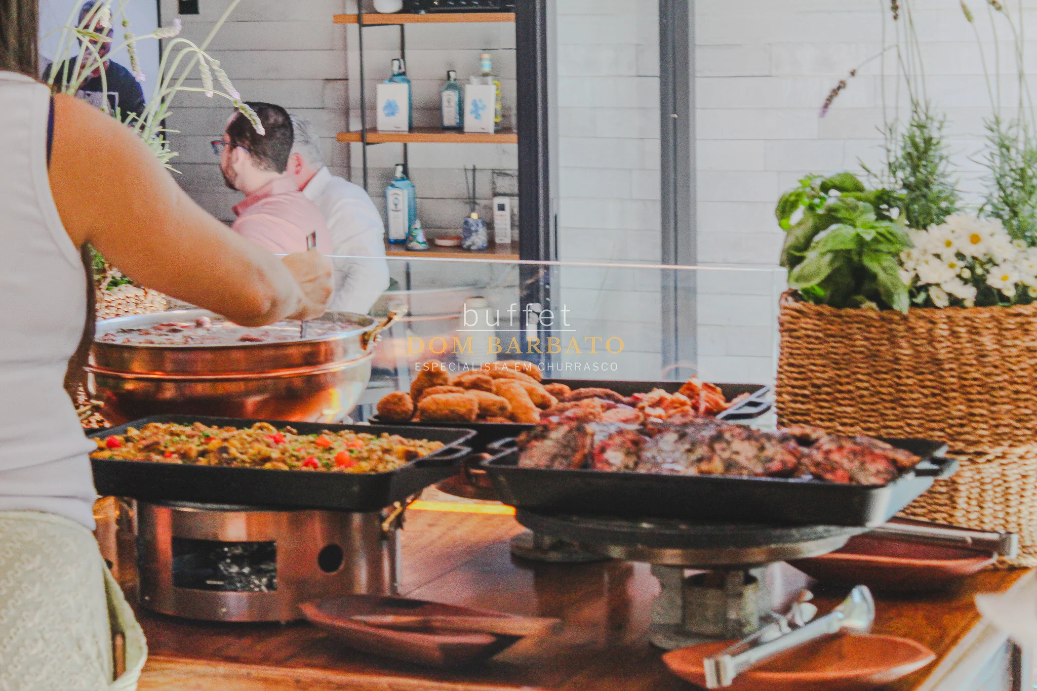 Bandejas de churrasco com carnes grelhadas, arroz, farofa e panela de cobre em buffet ao ar livre