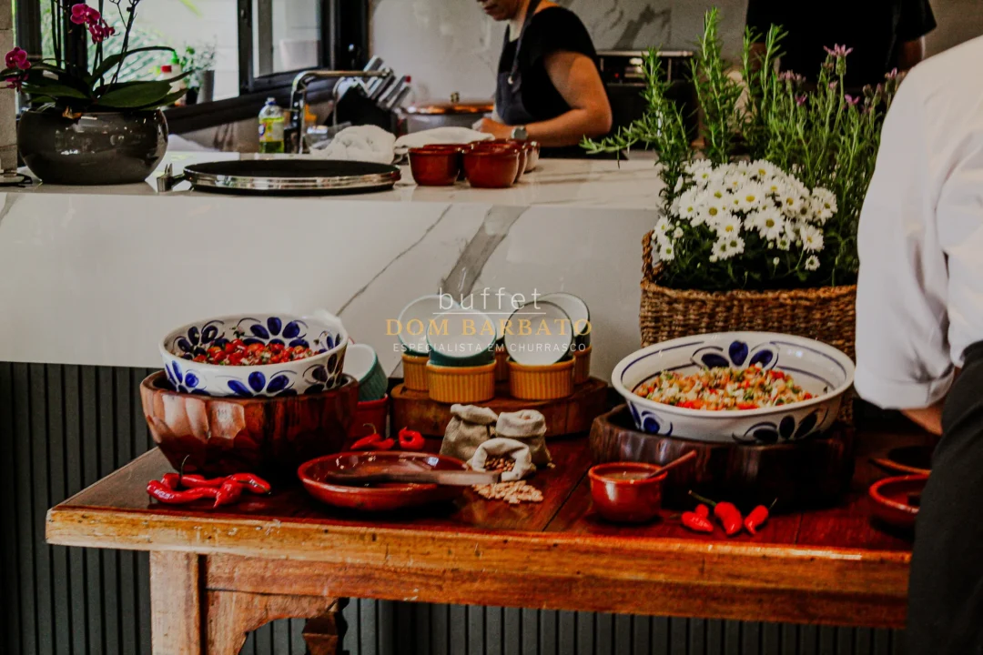 Mesa de madeira com tigelas decoradas de salada, pimentas vermelhas frescas e vasos de flores brancas