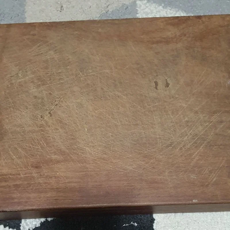 Superfície de madeira desgastada e arranhada, com tom marrom e textura porosa visível de perto