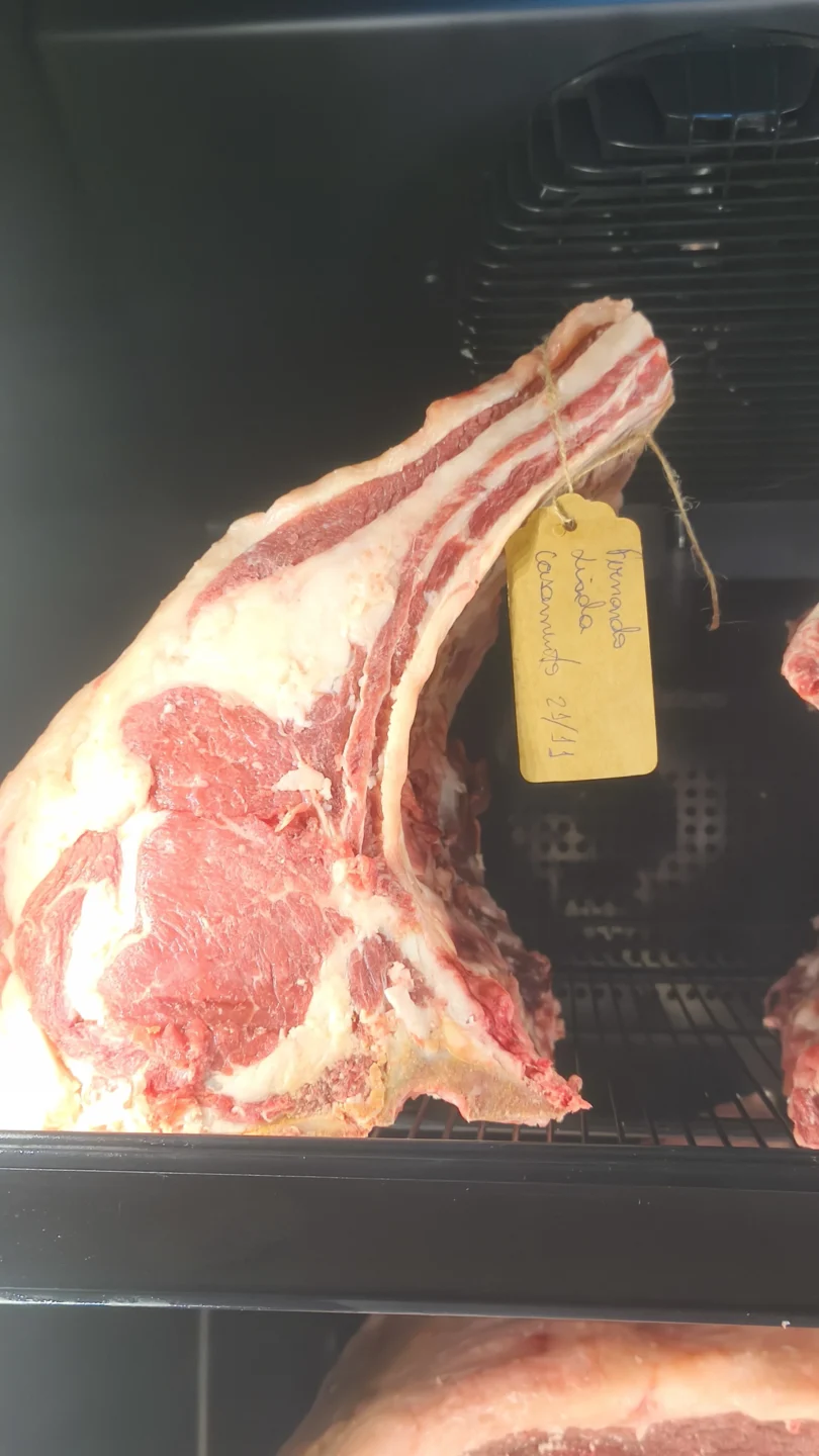 Peça de lombo bovino com osso em câmara refrigerada, com etiqueta kraft manuscrita pendurada